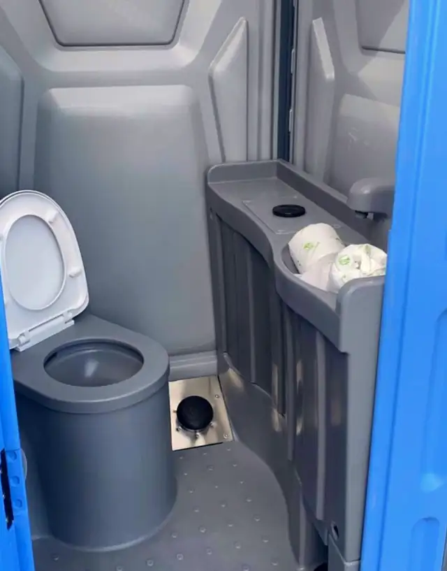 Deluxe porta potty interior with flushing toilet and hand-wash sink