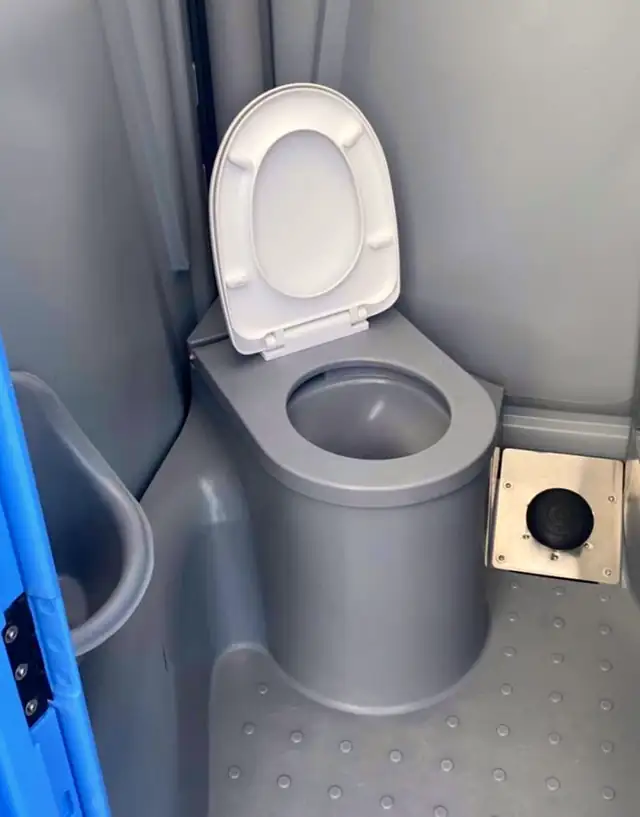 Deluxe portable toilet interior with a flushing bowl and lid