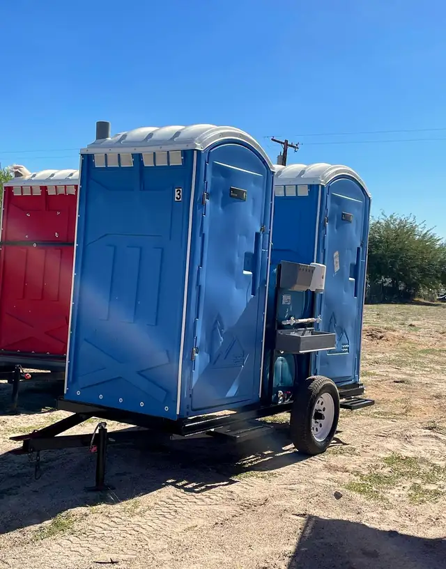 Porta potties on a towable trailer at an open jobsite