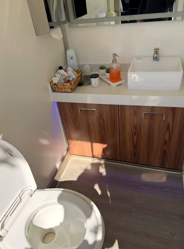 Luxury restroom trailer vanity with wood cabinets and vessel sink