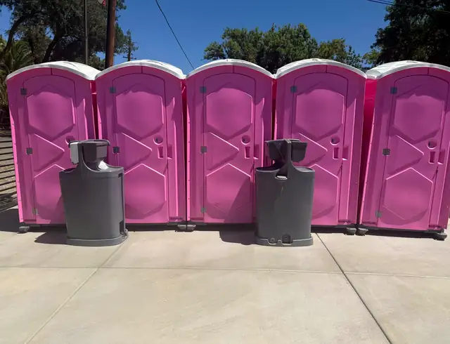 Row of pink porta potties with two handwashing stations for an event