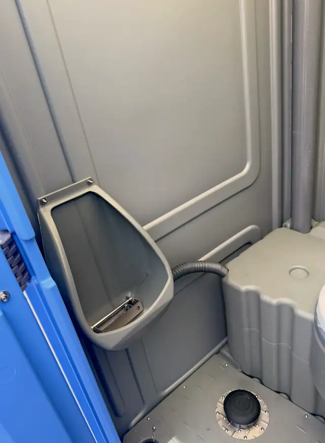 Porta potty interior showing urinal and anti-slip floor