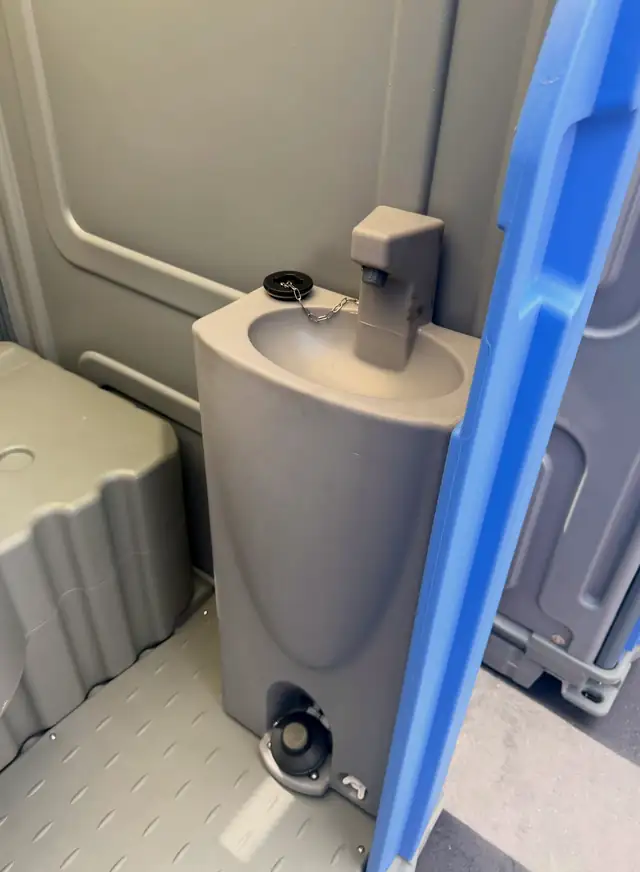 Porta potty interior with built-in hand-wash sink and soap