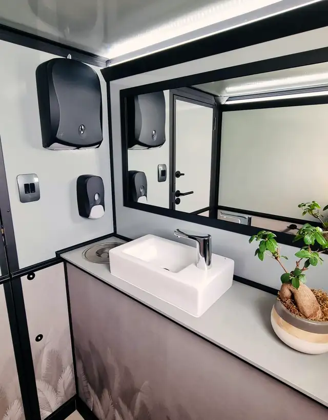 Restroom trailer vanity with vessel sink, mirror and soap dispensers