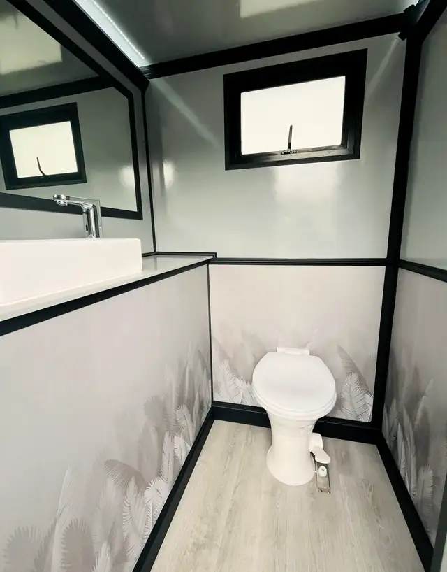 Restroom trailer stall with flushing toilet, vanity sink and window