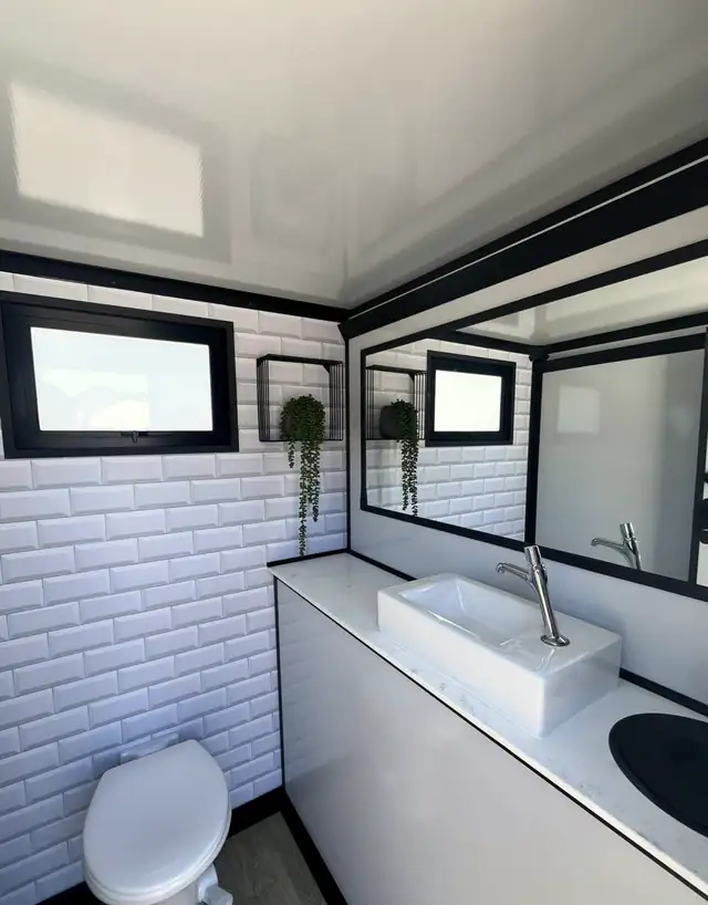 Restroom trailer interior with subway tile, sink and mirror