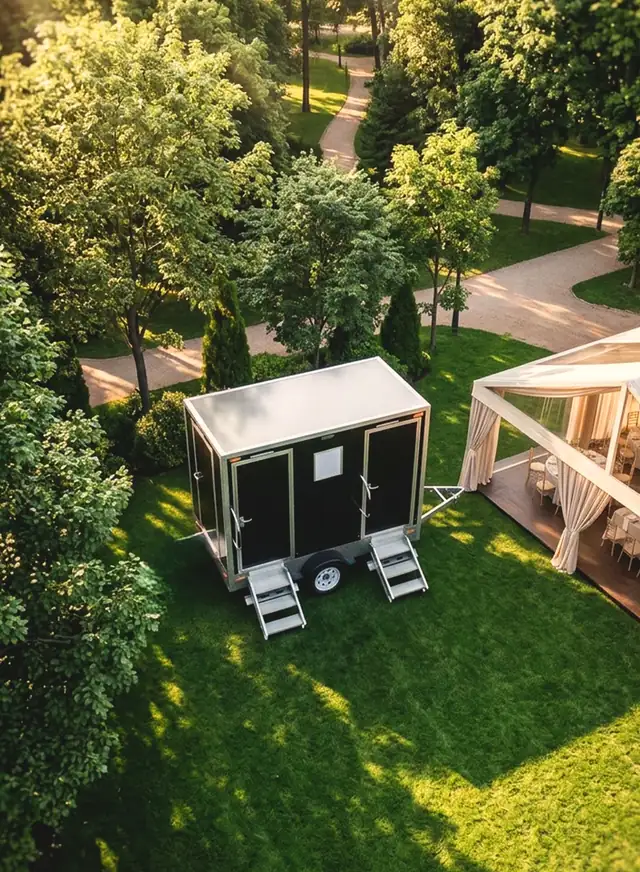 Aerial view of a restroom trailer beside a wedding tent on a green lawn