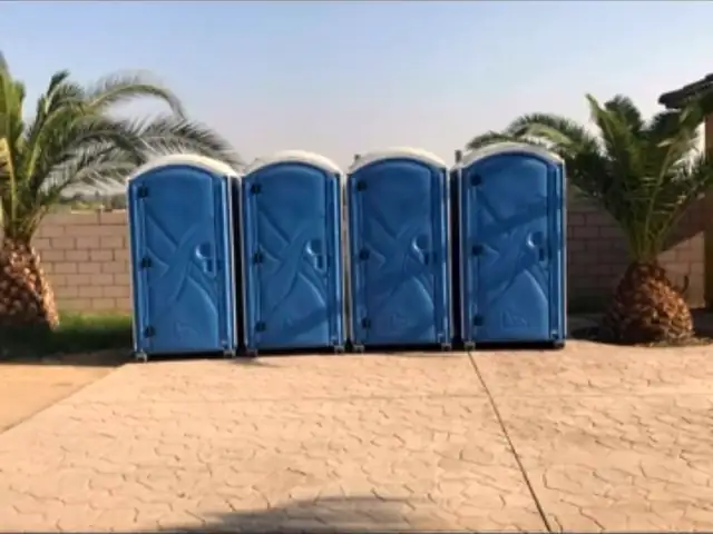 Row of four blue porta potties on a paved lot